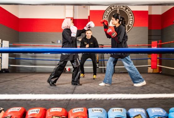 Two students in a boxing ring with professional boxer Tasif Khan Two students in a boxing ring with professional boxer Tasif Khan