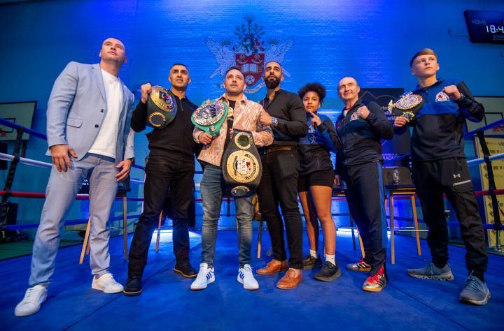 A group of people stand next to each other inside a boxing ring