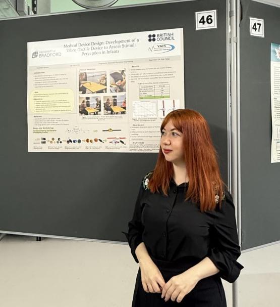 a student looks to the side in front of a poster on a board behind them a student looks to the side in front of a poster on a board behind them