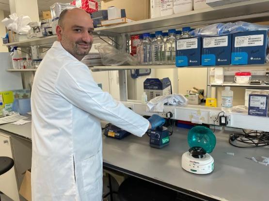 staff member wearing a white coat works inside a science lab staff member wearing a white coat works inside a science lab