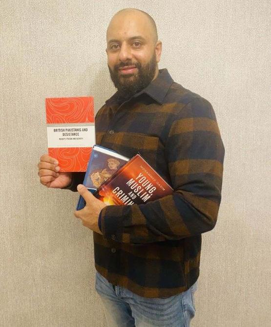 Staff member holds three book in their hands Staff member holds three book in their hands