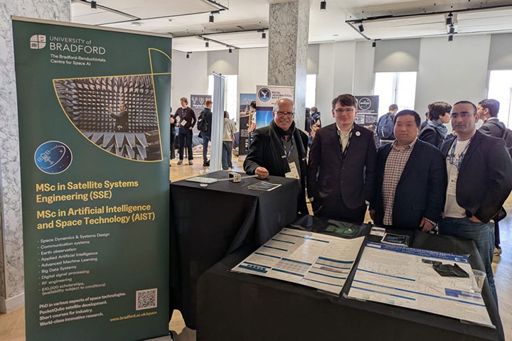Space AI centre representatives at a conference stand next to promotional banner Space AI centre representatives at a conference stand next to promotional banner