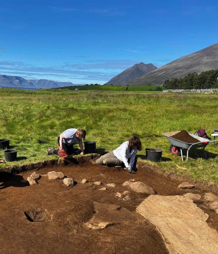 Two people take part in an archaeological dig with a blue sky backdrop Two people take part in an archaeological dig with a blue sky backdrop