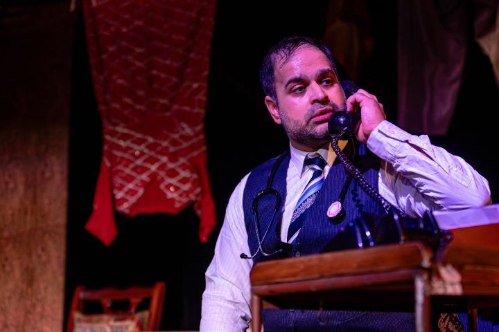 A person in a shirt, tie and waistcoat sat down speaking on a telephone A person in a shirt, tie and waistcoat sat down speaking on a telephone