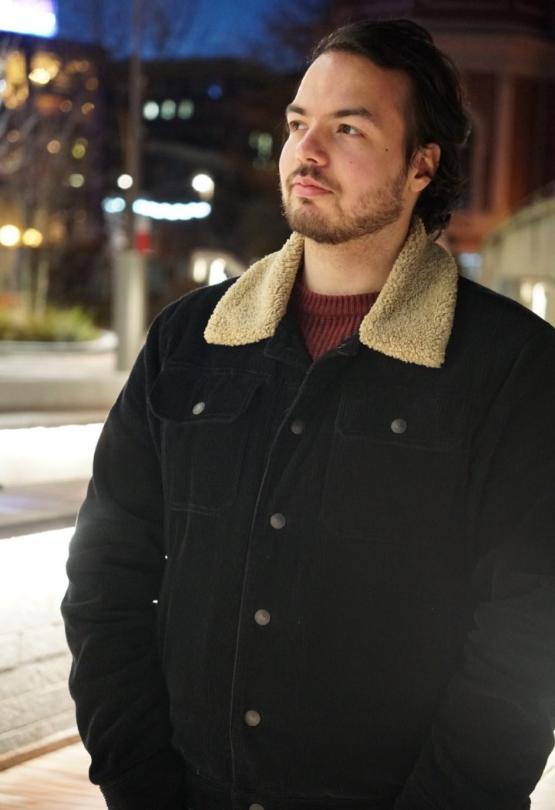 former student wearing a jacket looks into the distance in a street former student wearing a jacket looks into the distance in a street