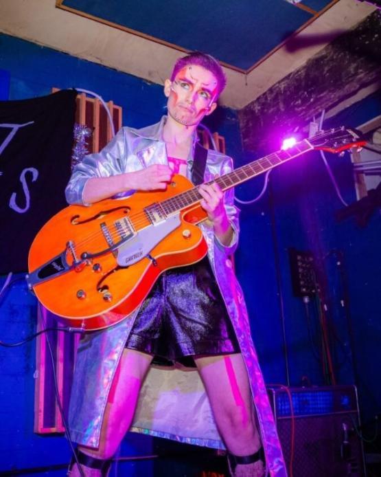 Person playing a guitar on stage during an entertainment show Person playing a guitar on stage during an entertainment show