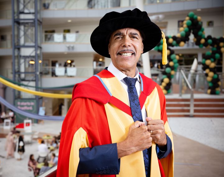 a smiling person dressed in graduation gowns