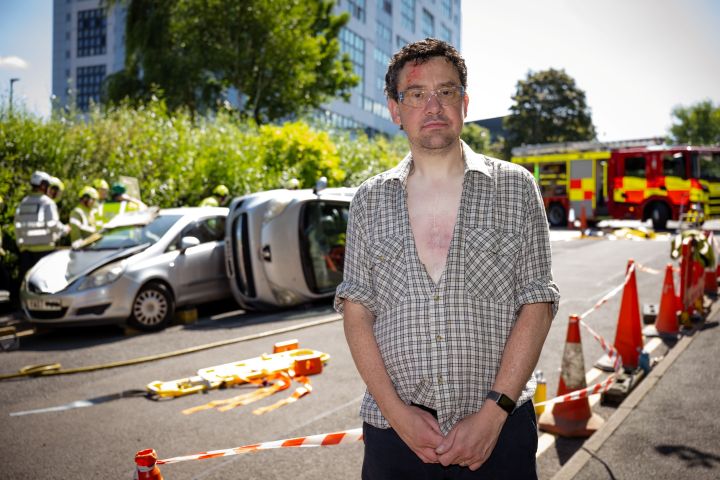 A crash victim in a shirt stands in front of a scene A crash victim in a shirt stands in front of a scene