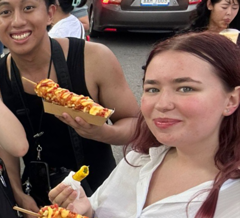 A group of young people pose with food from a market