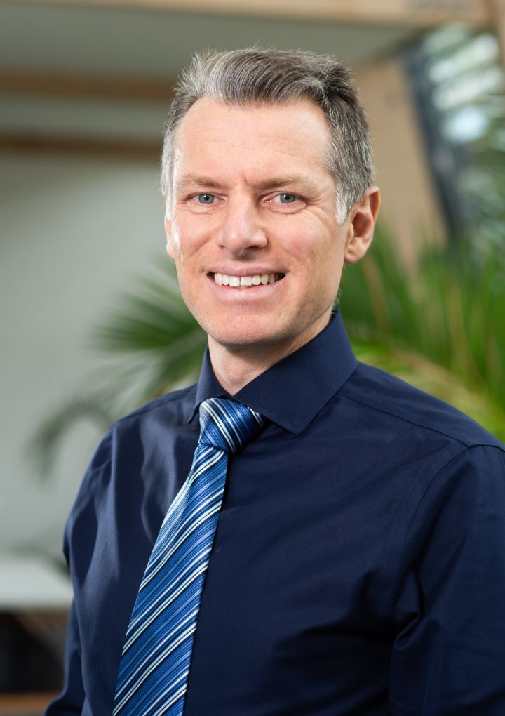 A head and shoulders photo of person dressed in a shirt and tie smiling A head and shoulders photo of person dressed in a shirt and tie smiling