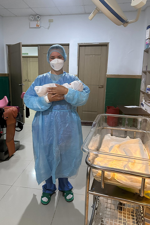 Courtney holding a baby whilst wearing scrubs. Courtney holding a baby whilst wearing scrubs.