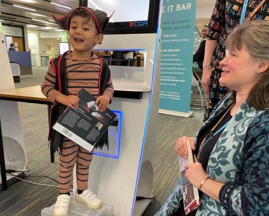 A youngster stood up holding a book inside a library A youngster stood up holding a book inside a library