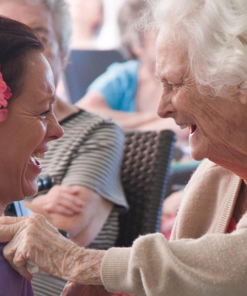 Elderly person and careworker laughing together.