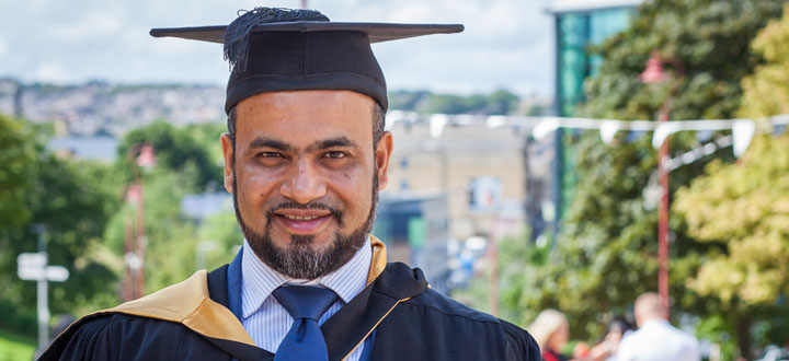 A person dressed in graduation attire, smiling at the camera.