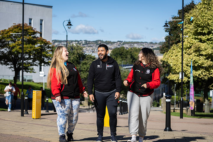 Three students laughing together on campus