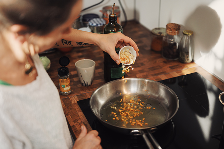 Person pouring spices into a frying pan