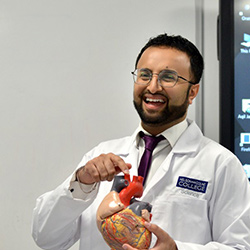 A student wearing a labcoat smiling at the camera
