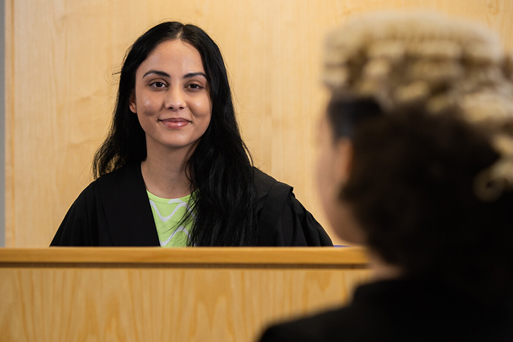 A student smiling at the camera sitting in the law court