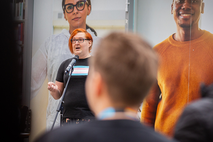 A student speaking at an event in the Atrium as an audience member looks on