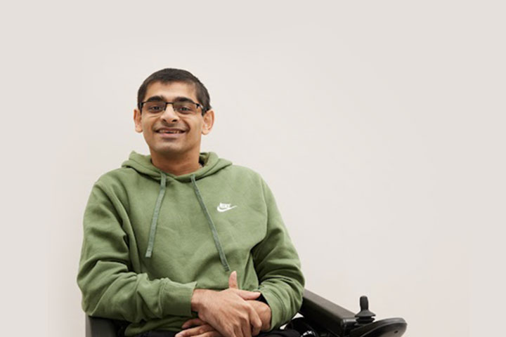 A wheelchair using student smiling at the camera