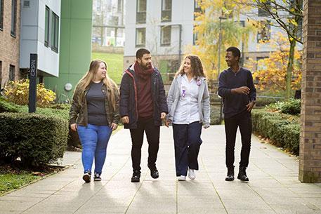 Four students walking through student accommodation on campus.