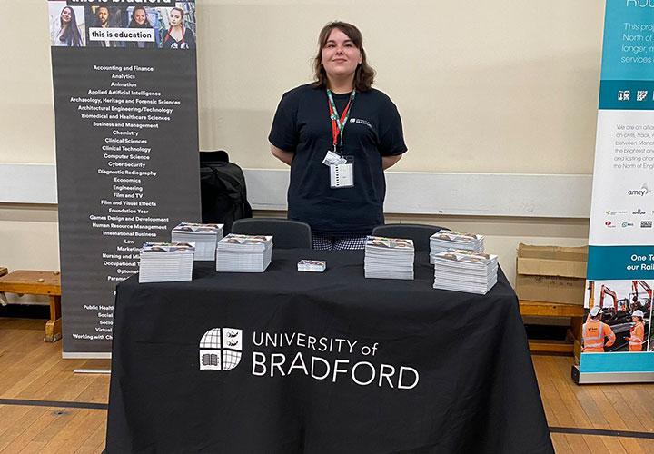 Student standing behind a University of Bradford stand.