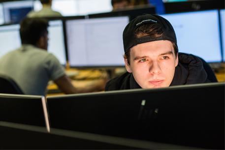 Student wearing a hat looking at a computer screen in a classroom
