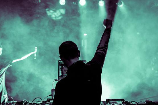 A DJ raising his fist while performing on stage