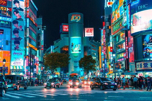 Tokyo crossing at night, buildings and signs lit up in bright colours. (Unsplash)