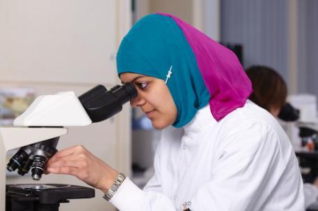 A female student looking into a microscope
