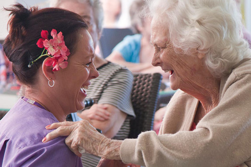 A student nurse and elderly patient laughing together.