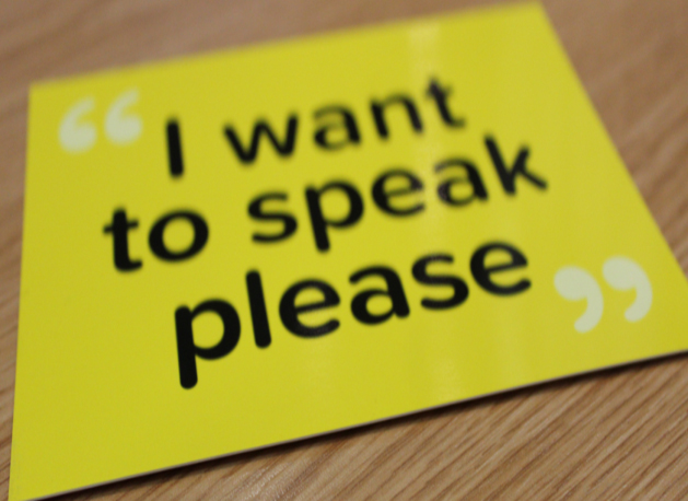 A yellow sign with black text that says 'I want to speak please'.