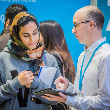 An academic talking to a prospective student on an open day