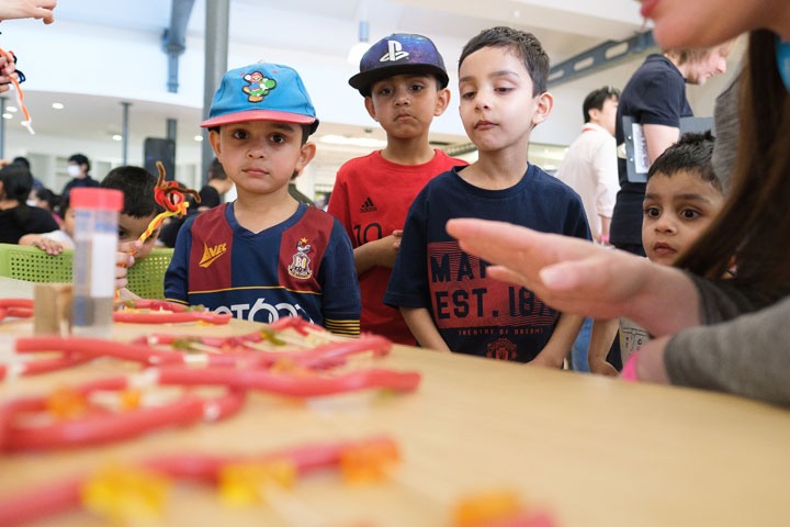 A group of young boys being shown how to replicate DNA strands using sweets