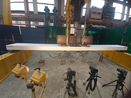 Heavy machinery applying pressure to a concrete beam to test its strength