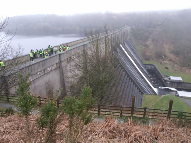 Students wearing high-vis jackets and hard hats standing on a dam in Whitby.