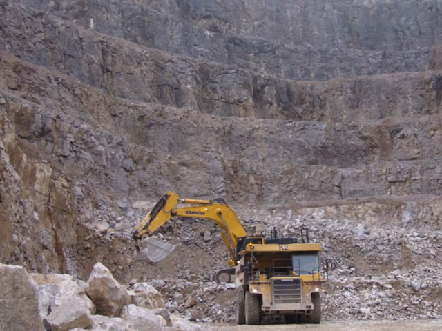 A yellow digger in a quarry.