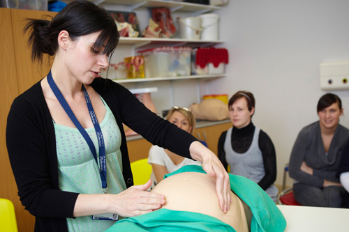 A student midwife feeling the stomach of one of our practice mannequins.