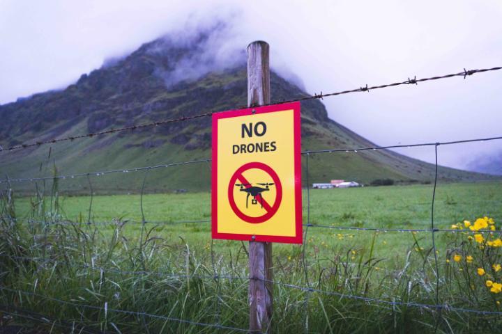 Sign saying 'no drones' on barbed wire fence protecting area of natural beauty