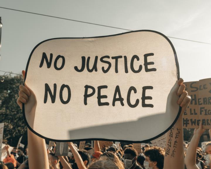 Banner being held up saying 'no justice, no peace'
