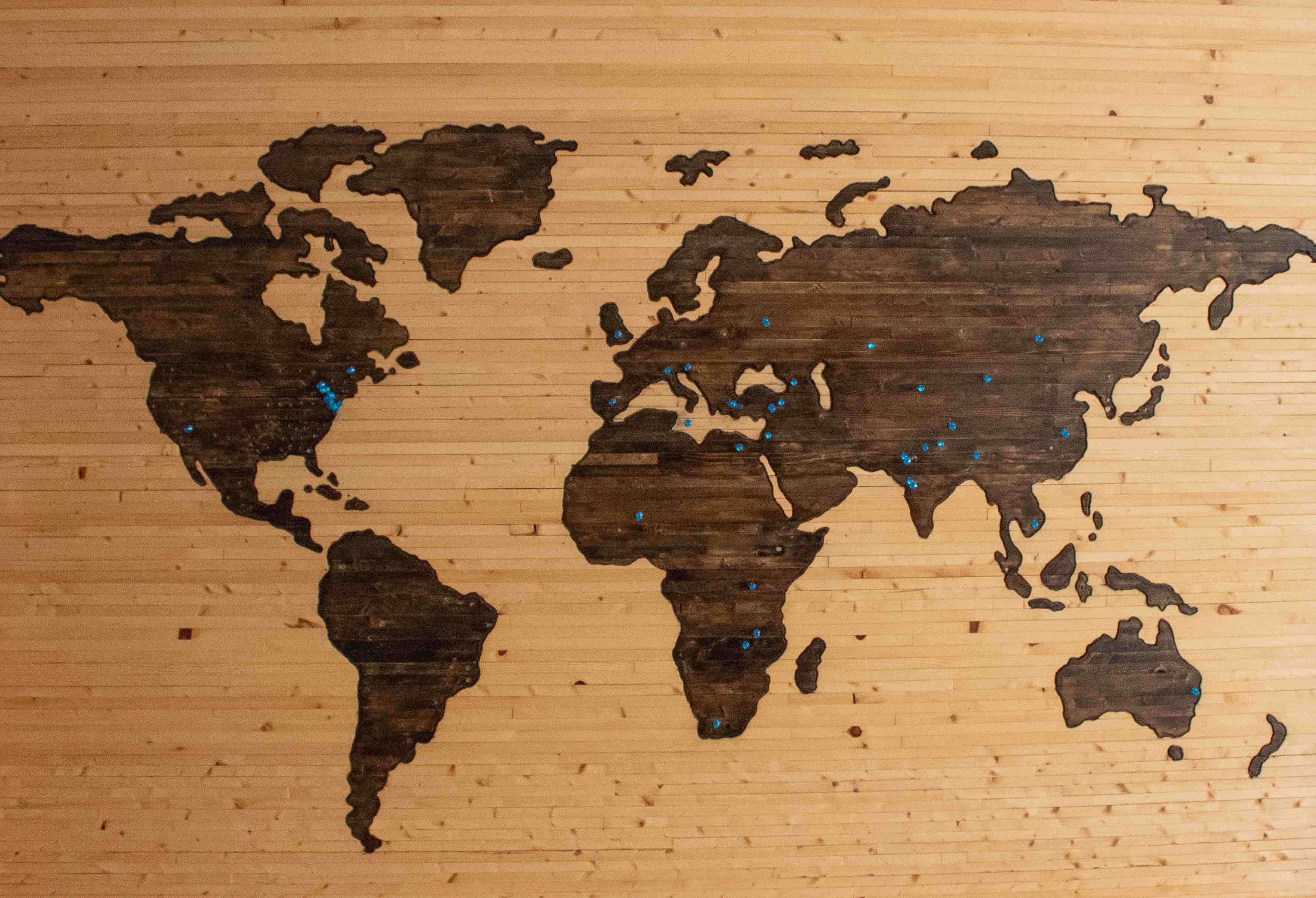 World map made of wood with blue flags to mark places
