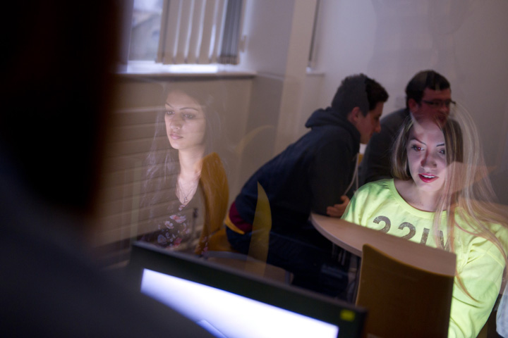 Three students observing a group of people through a two way mirror in the Department's Observation suite.