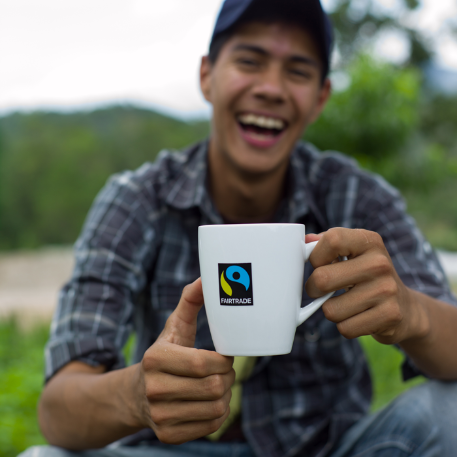 Man out of focus smiles whilst holding a fairtrade cup in Hondorus
