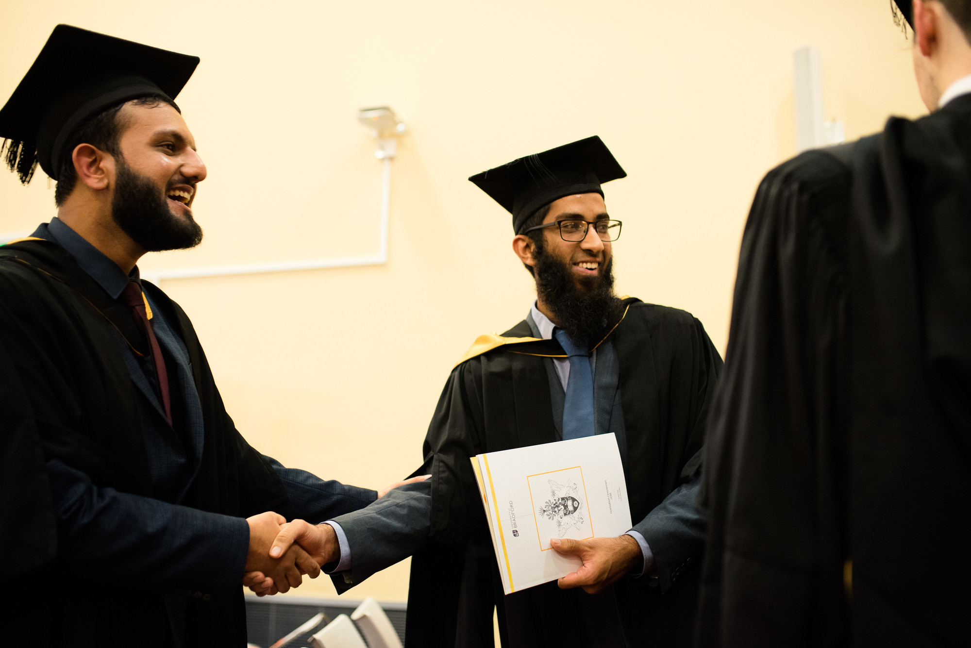 Two graduates shaking hands