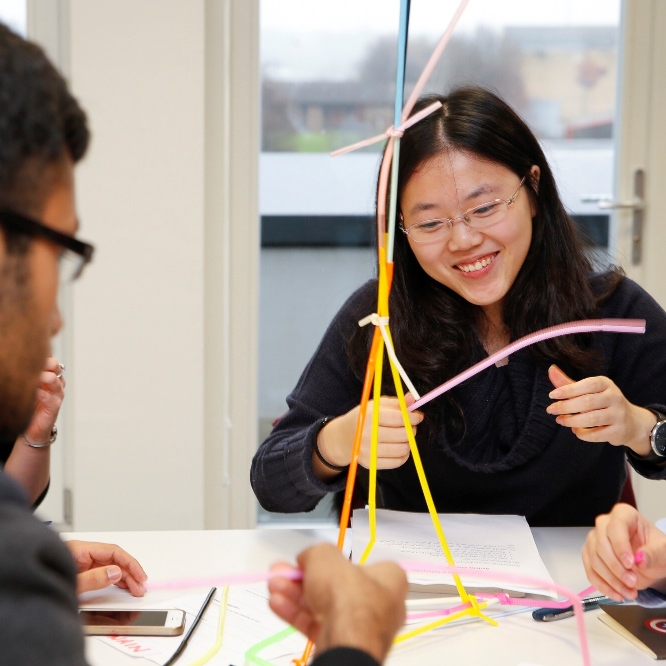 A student engaging in mock assessment centre activity (building a structure with straws) with employer representatives observing