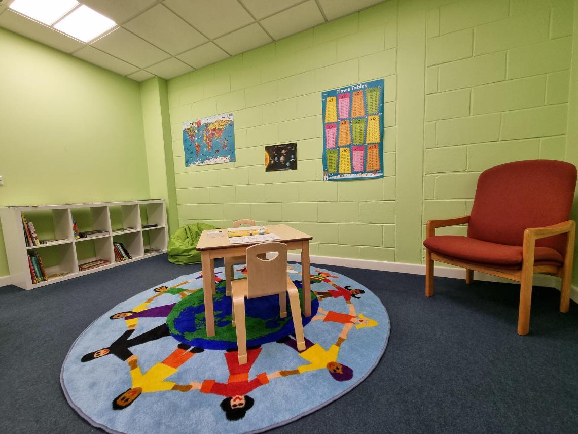 A brightly coloured room with children's furniture and books