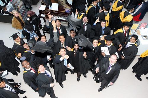 Graduation student throwing mortar boards into the air towards the camera