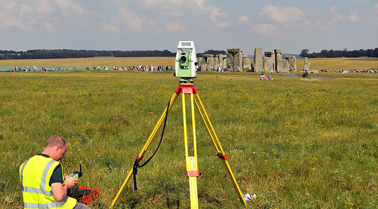 A person using archaeology equipment infront of Stone Henge.
