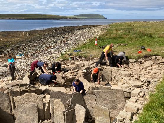 Several people at a coastal archaeological site searching for artefacts