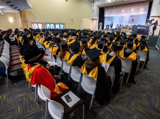 Students in graduation robes sat in their ceremony